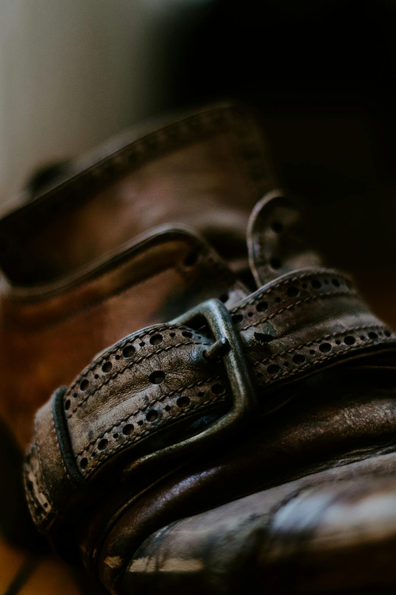 Close-up of a vintage leather boot focusing on the intricate buckle design in soft light.
