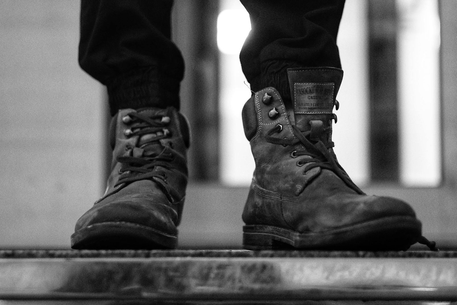 Tough leather boots worn outdoors, highlighting rugged style in monochrome.