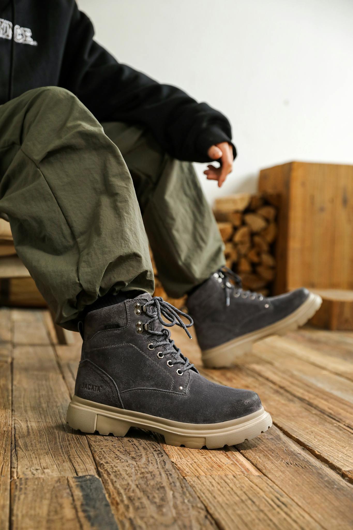 A casual shot of black boots worn on a wooden floor.
