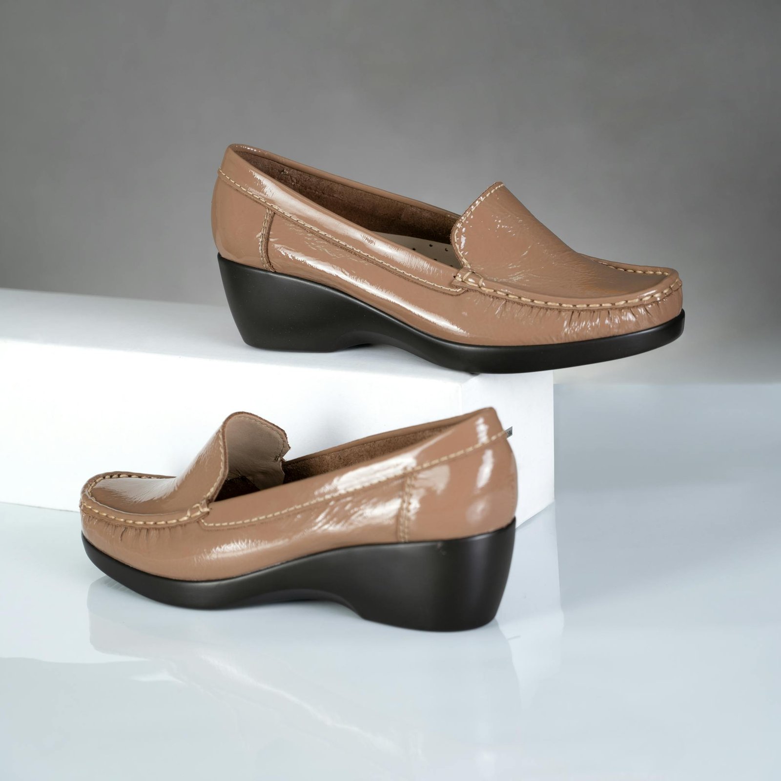 Elegant beige leather moccasins with wedge heels showcased on a minimalist display